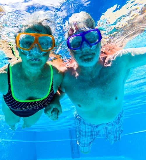 senior couple swimming in pool underwater